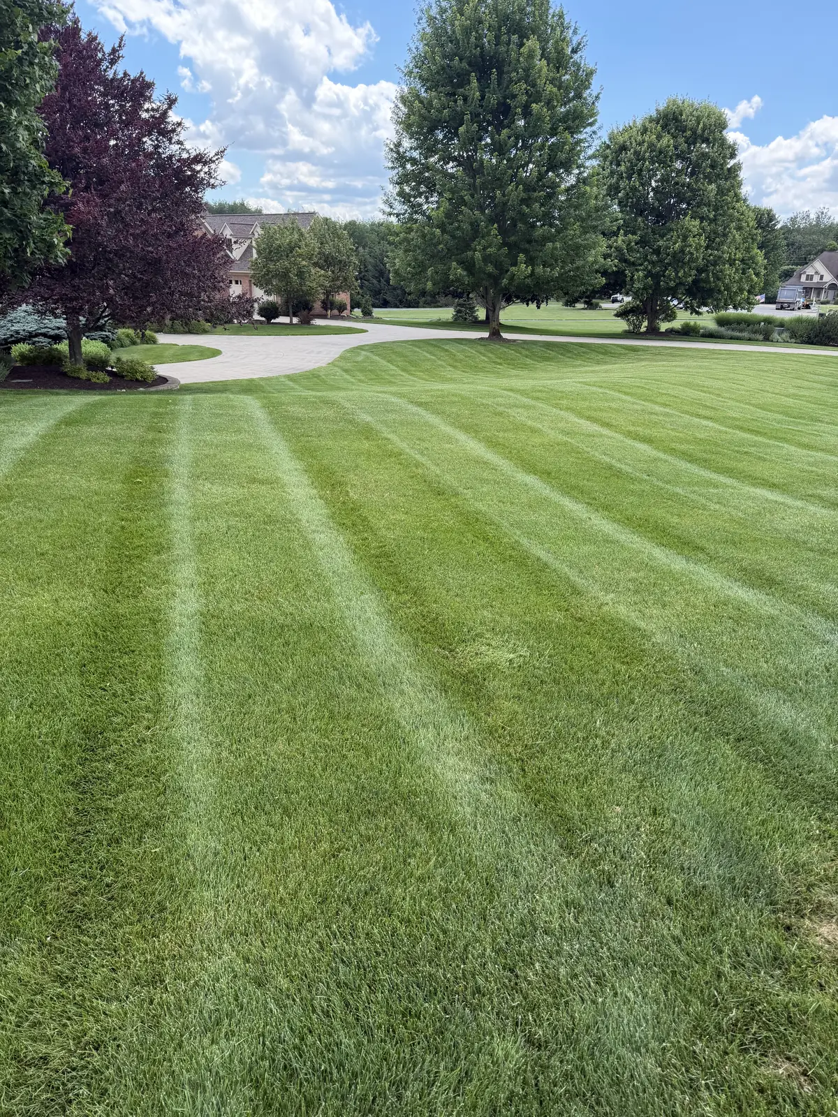 Striped lawn wrapping around a circular paver driveway